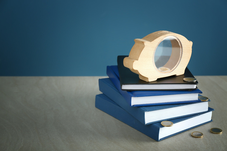 Piggy bank, coins and stack of books on table. Concept of savings for educationの写真素材