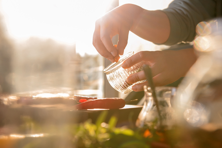 Woman putting sliced chili pepper into jarの写真素材