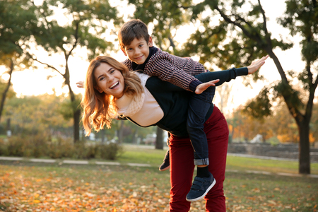 Happy mother and son playing in autumn parkの写真素材