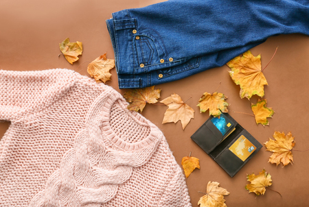 Stylish outfit with wallet and autumn leaves on color background, top viewの写真素材