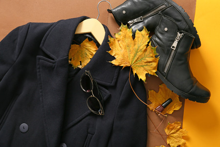 Stylish coat with boots and autumn leaves on color background, top viewの写真素材
