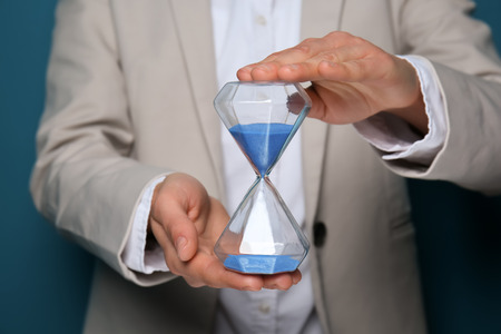 Office worker holding hourglass, closeup
