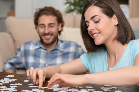 Young couple doing jigsaw puzzle at homeの写真素材