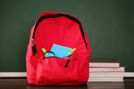 Backpack with school supplies near chalkboardの写真素材