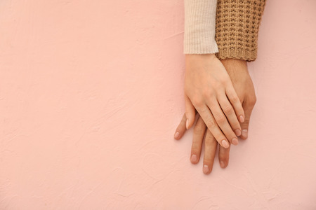 Hands of loving young couple on color backgroundの写真素材