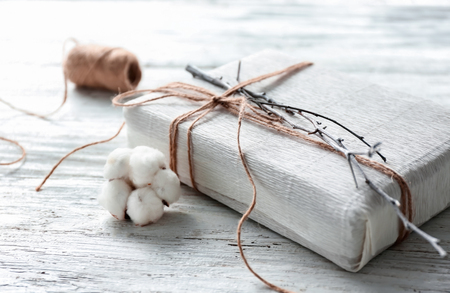 Gift box with cotton flower on light wooden tableの写真素材