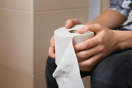 Woman with roll of toilet paper in restroom, closeupの写真素材