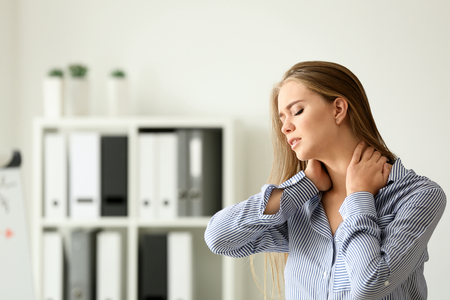 Young woman suffering from neck pain in officeの写真素材