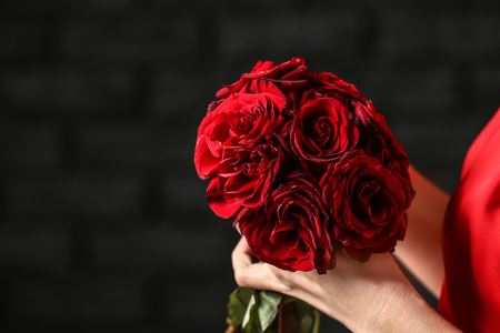 Woman with bouquet of beautiful roses on dark background, closeupの写真素材