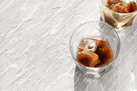 Glasses with coffee ice cubes on tableの写真素材