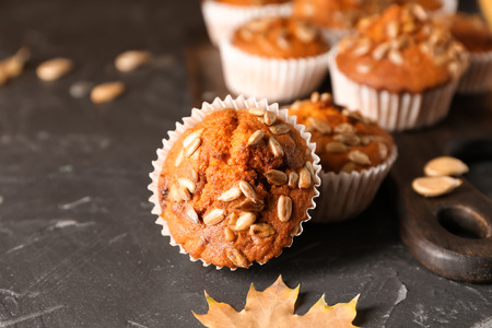Fresh pumpkin muffins with sunflower seeds on dark tableの写真素材