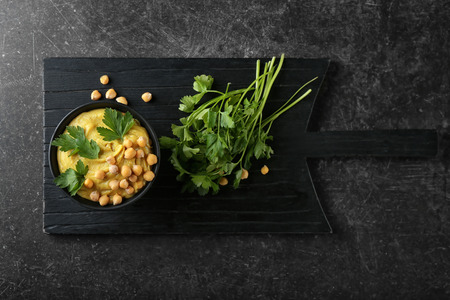 Bowl with tasty hummus on dark tableの写真素材