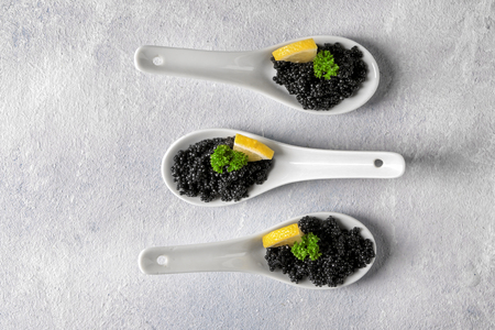 Spoons with delicious black caviar on light tableの写真素材
