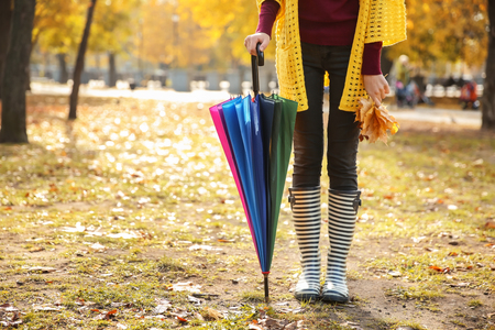 Beautiful fashionable woman with umbrella in autumn parkの写真素材