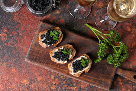 Delicious sandwiches with black caviar on wooden boardの写真素材