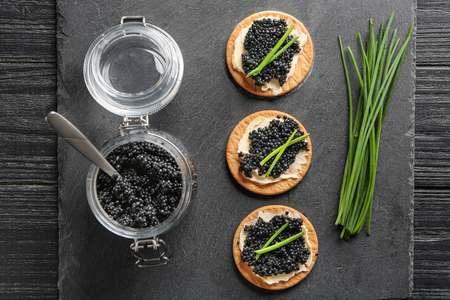 Jar and cookies with delicious black caviar on slate plateの写真素材