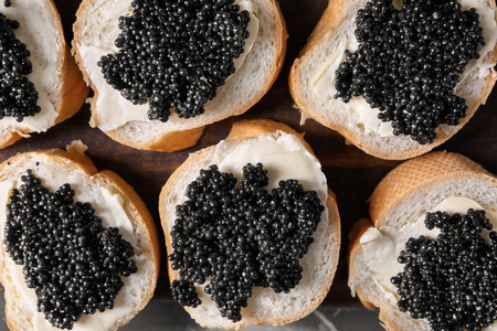 Delicious sandwiches with black caviar on wooden board, closeupの写真素材