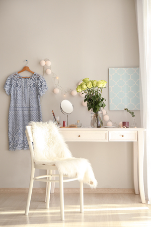 Vase with beautiful green roses and female items on white table in roomの写真素材