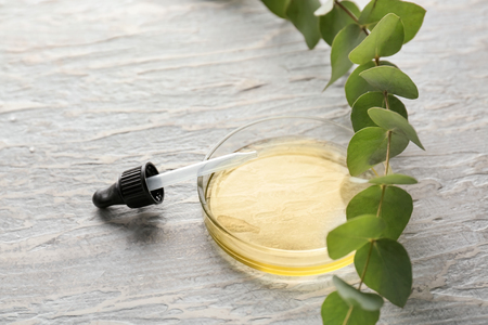 Glass dropper and bowl with eucalyptus essential oil on white tableの写真素材