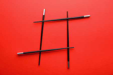 Hashtag sign made of chopsticks on color background