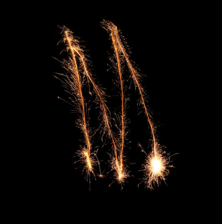 Sparklers forming letter M on dark background