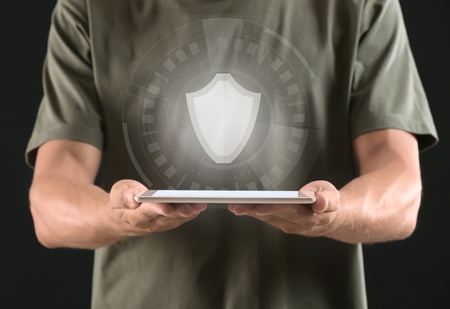 Man with tablet PC and shield icon on dark background. Data security conceptの写真素材