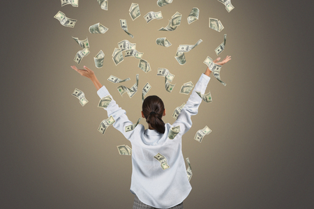Happy rich woman with dollar banknotes on grey backgroundの写真素材