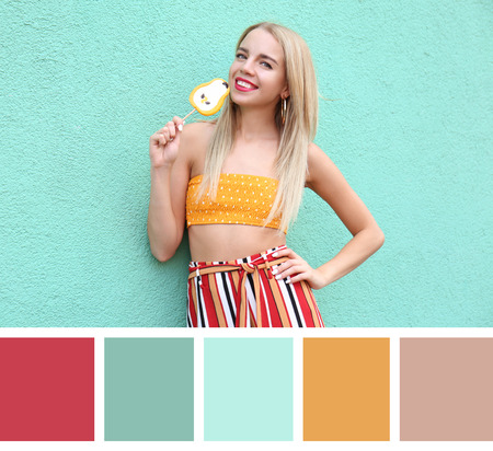 Beautiful young woman with lollipop near color wall. Different color patternsの写真素材