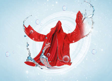 Flying clean clothes with splashes of water on color backgroundの写真素材