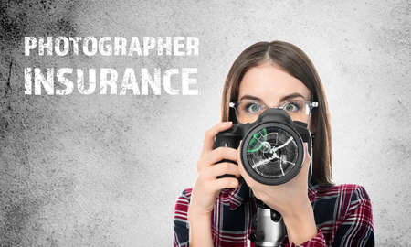 Young female photographer with damaged photo camera on gray background with text PHOTOGRAPHER INSURANCEの写真素材