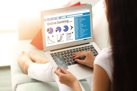 Woman with credit card using laptop for online banking at homeの写真素材