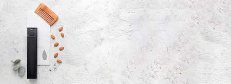 Composition with shampoo, comb and natural ingredients on light background with space for text