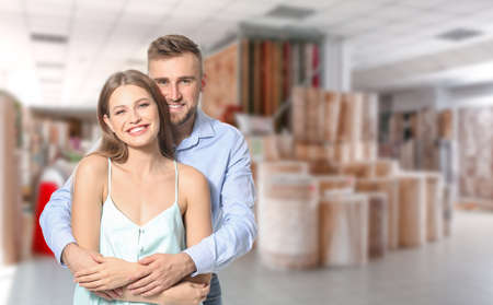Happy young couple in modern carpet shopの写真素材