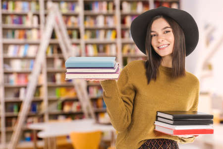 Beautiful young woman with books in modern library