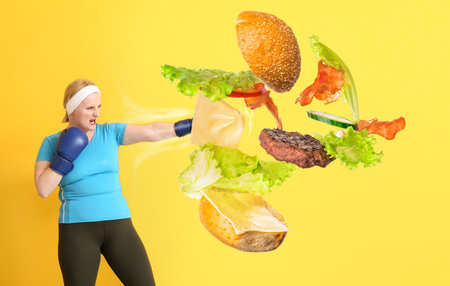 Woman with excess weight kicking burger on color backgroundの写真素材