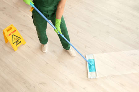 Male janitor mopping floor in roomの写真素材