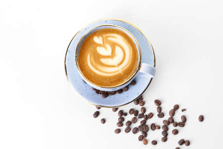 Cup of tasty cappuccino and coffee beans on white background