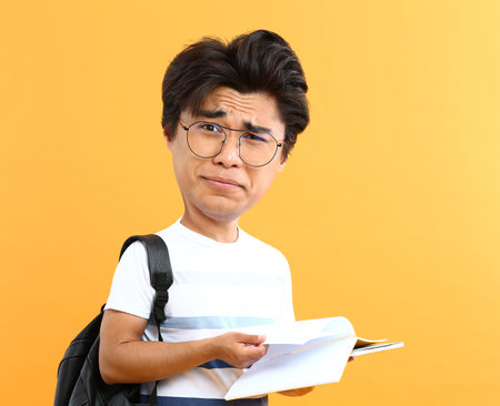 Stressed male Asian student with big head on color backgroundの写真素材