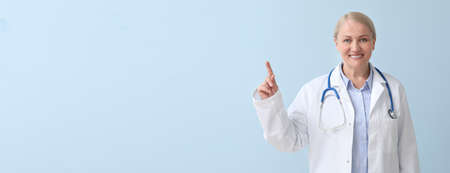 Mature female doctor on color background with space for textの写真素材