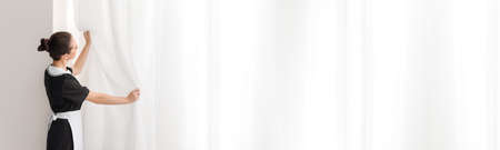 Beautiful female chambermaid near window in roomの写真素材