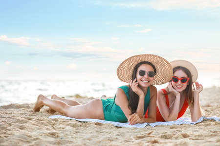 Beautiful young women lying on sea beach at resortの写真素材