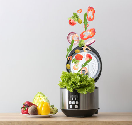 Products falling into modern multi cooker on table against light background