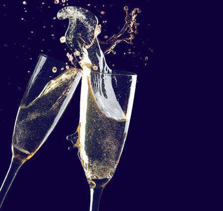 Clinking glasses of champagne with splash on dark backgroundの写真素材