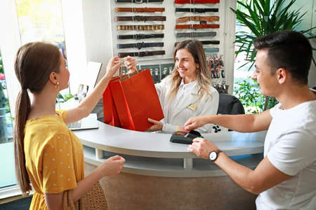 Female seller working with couple in modern shopの写真素材