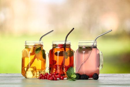 Mason jars of cold cocktails on table outdoorsの写真素材