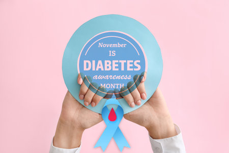 Female hands with blue ribbon and text NOVEMBER IS DIABETES AWARENESS MONTH on color backgroundの写真素材