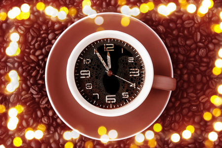 Cup with clock on coffee beans with blurred lights