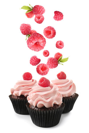 Delicious cupcakes and falling raspberry on white backgroundの写真素材