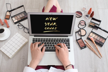 Female makeup artist with laptop making to do list at homeの写真素材