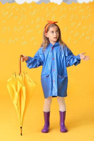 Cute little girl in raincoat and with umbrella under drawn rain drops on color backgroundの写真素材
